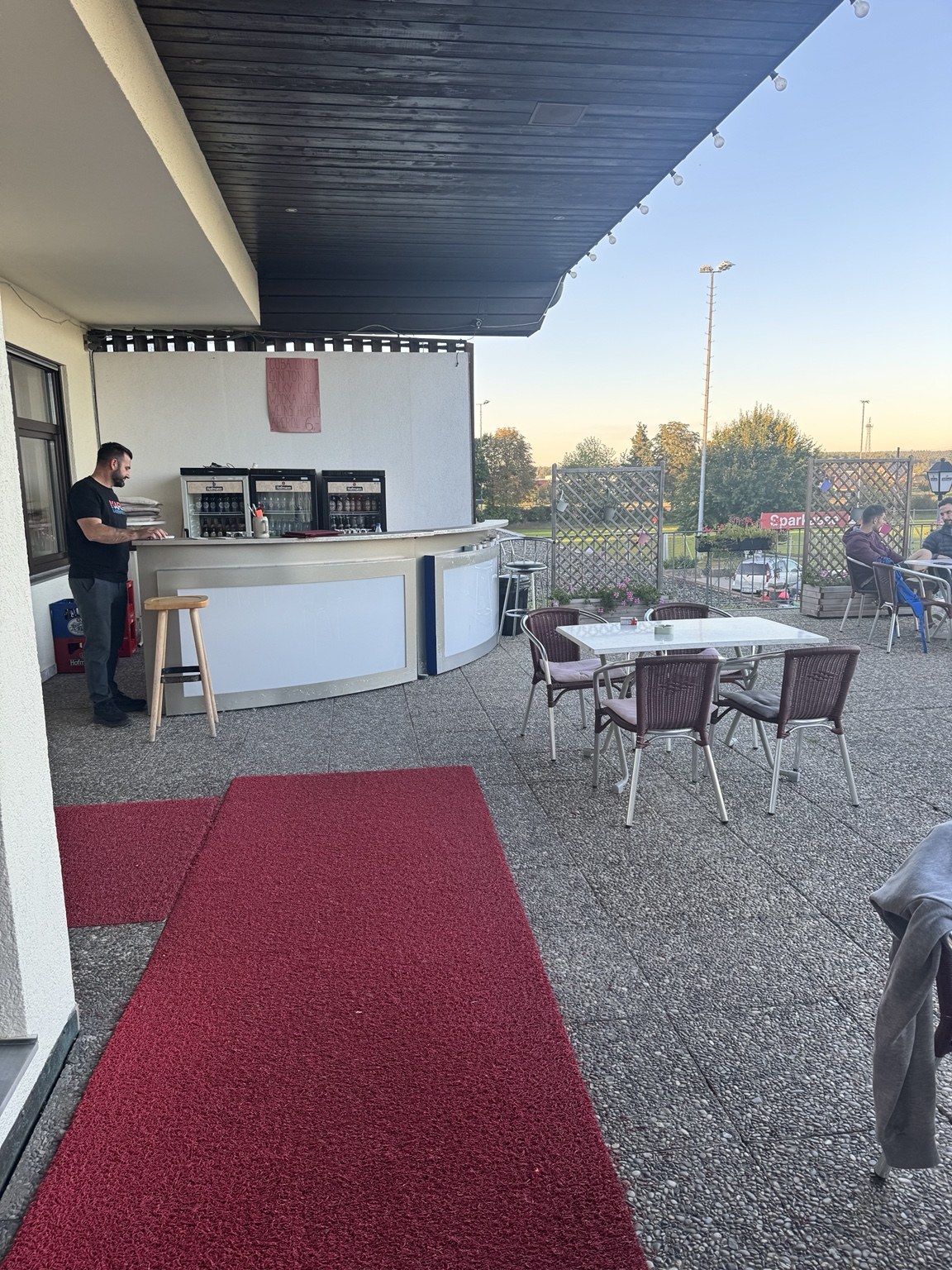 Großzügige Terrasse mit Sonnenschirmen und Blick auf das Sportgelände
